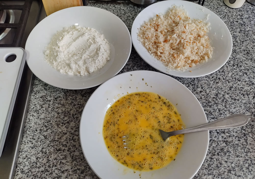 Platos con harina, huevo batido y pan rallado